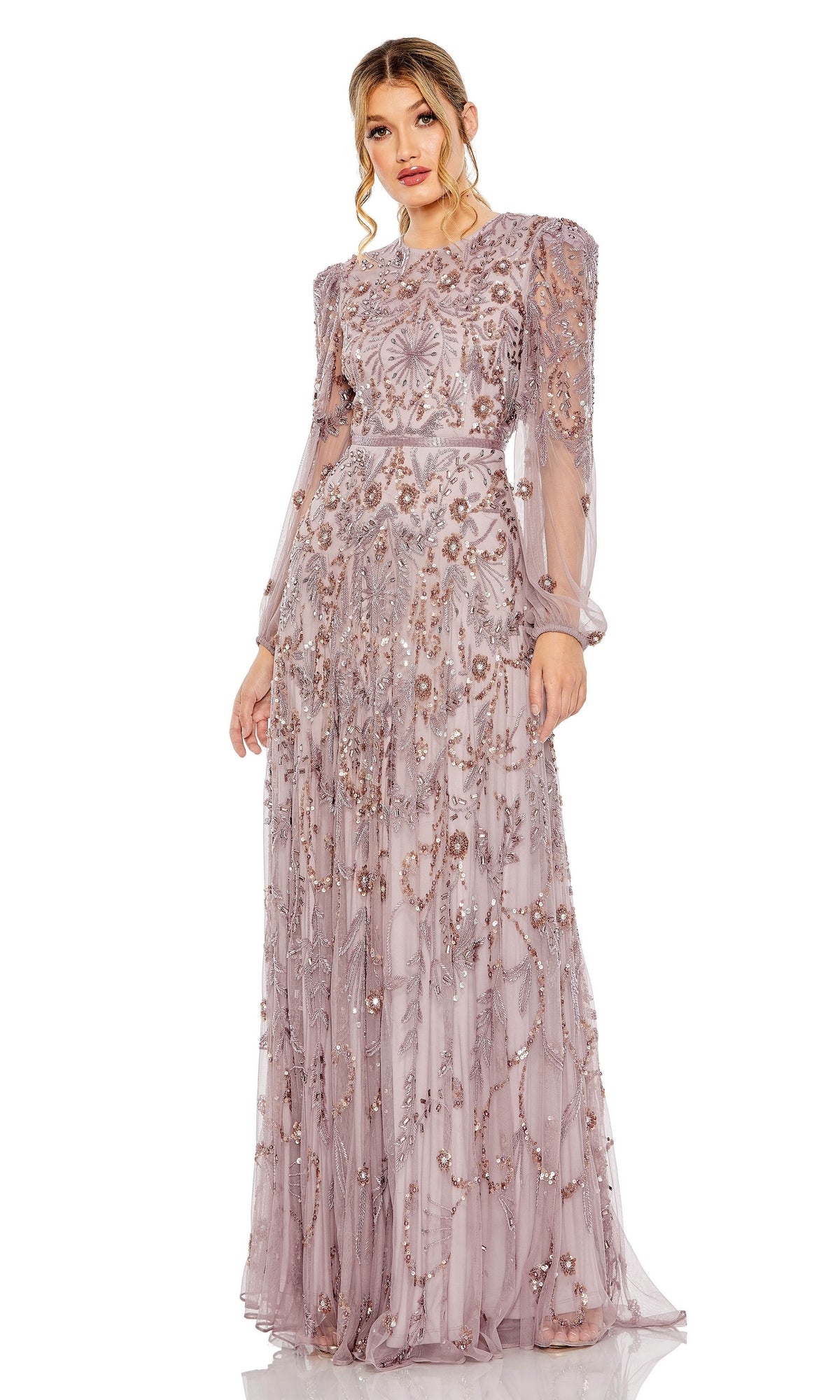 A woman wears the Mac Duggal 93930—a long sleeve beaded formal gown in sheer light purple, detailed with intricate floral embroidery and sparkling beadwork, featuring a floor-length skirt.